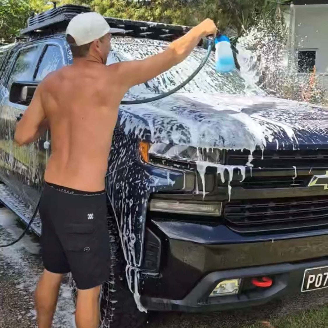 4WD owner using Clean Offroad Starter Pack Foam Gun with garden hose for easy vehicle cleaning at home